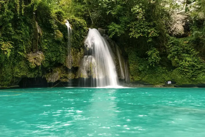 Kawasan Falls pouring into a turquoise pool in the green hills of Cebu